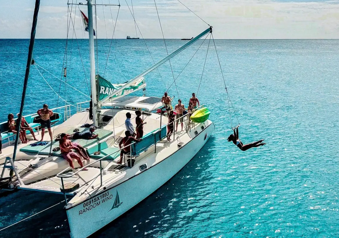 Guests on the Random Wind catamaran with Tarzan swing above the sea