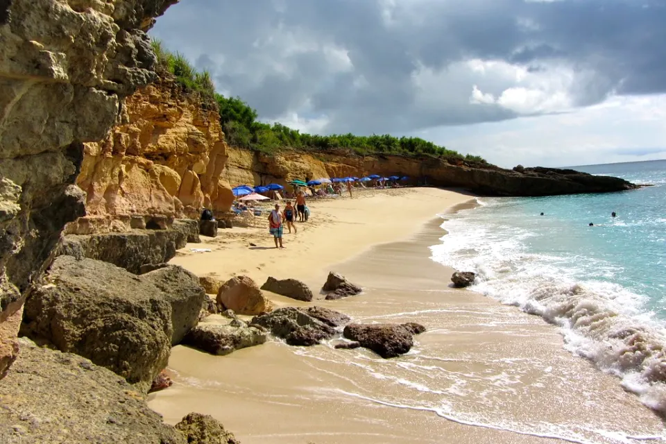 Cupecoy Beach below ochre cliffs with loungers and waves on the shoreline