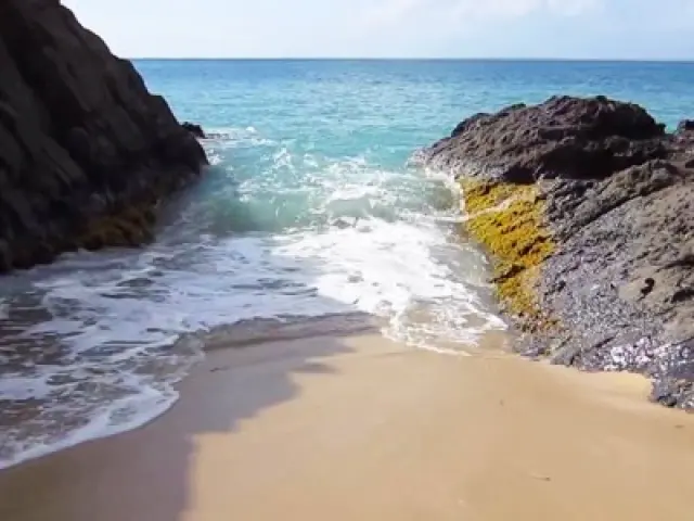 Narrow Lovers Beach shoreline with waves between rocks