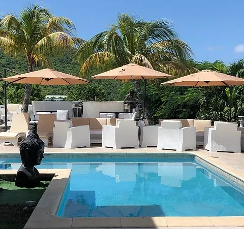 Daytime pool and lounge at 978 Sanctorum with beige parasols, palms and a Buddha statue