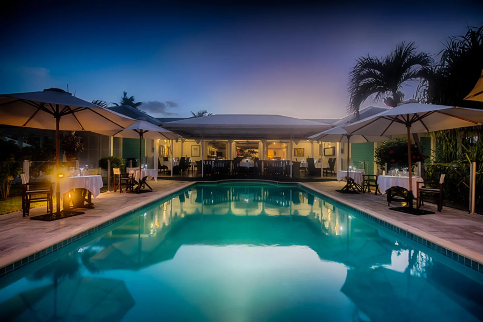 L'Astrolabe at dusk: lit pool and white-linen tables around the restaurant at Esmeralda Resort