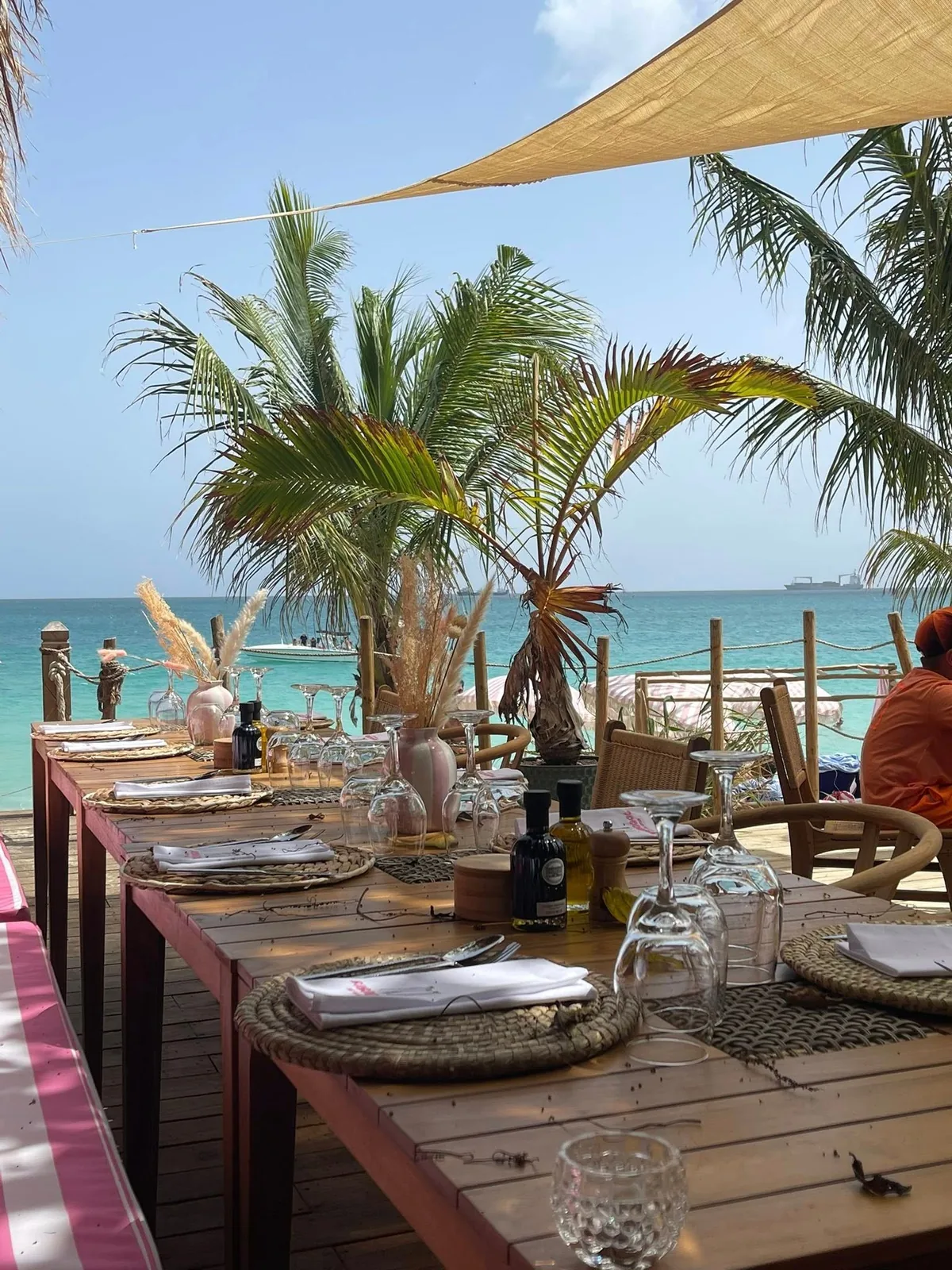 Table set facing the turquoise sea at Babacool lunch, palm trees and boats offshore