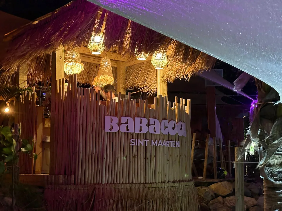 Wood and bamboo dining room at Babacool with pink-striped benches and beachfront tables