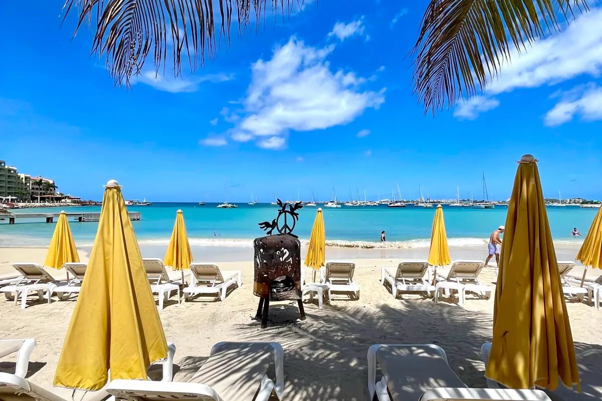 Beach chairs and yellow umbrellas at Buccaneer Beach Bar facing the lagoon