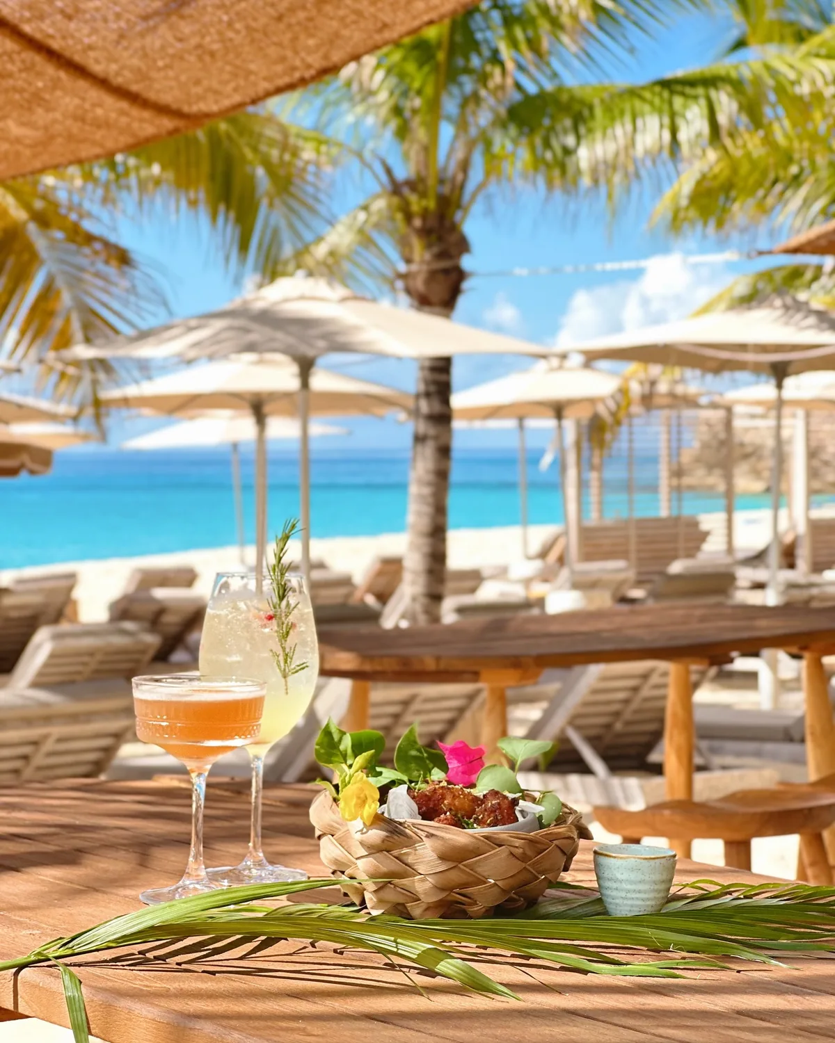 Cocktails and mezze on a wooden table by the beach at Kalatua, Tulum-style vibe