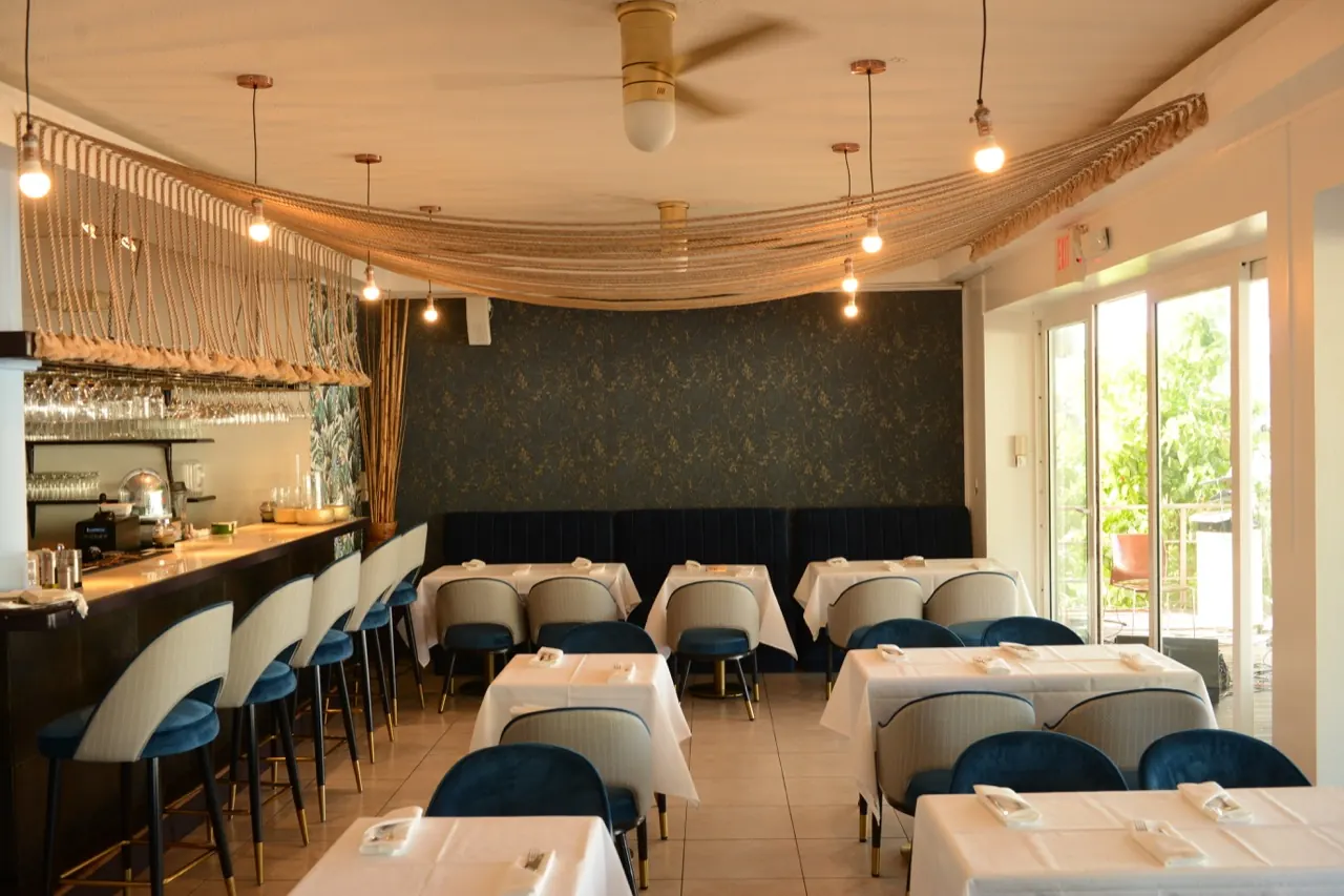 La Perle Bleu indoor dining room with set tables, bar and white and blue decor