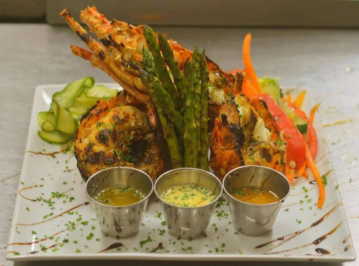 Fish and lobster dish served with vegetables and house sauces at La Perle Bleu