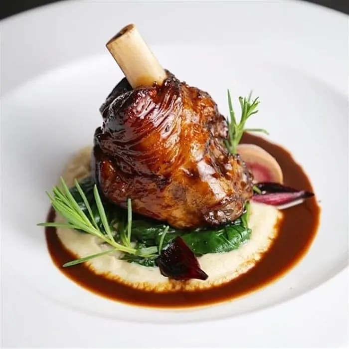 Red wine-braised lamb shank served with mashed potatoes and reduced jus at La Perle Bleu