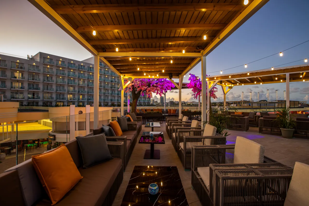 Tables and sofas at the Mimosa Skylounge rooftop under the lit-up bougainvillea