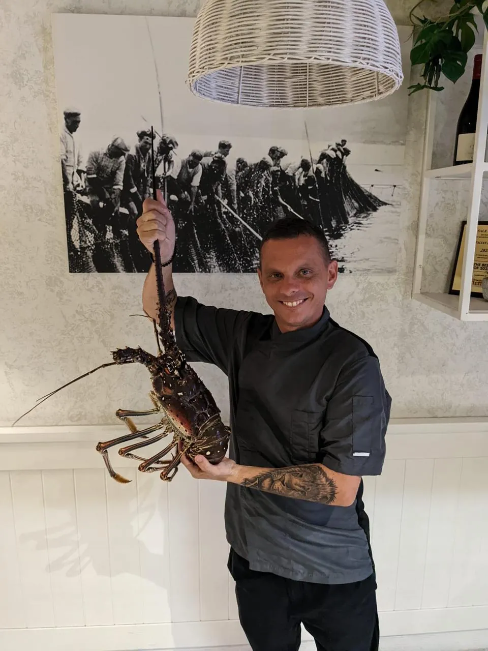 Chef Davide Zagami holding a fresh spiny lobster inside the Sale & Pepe dining room