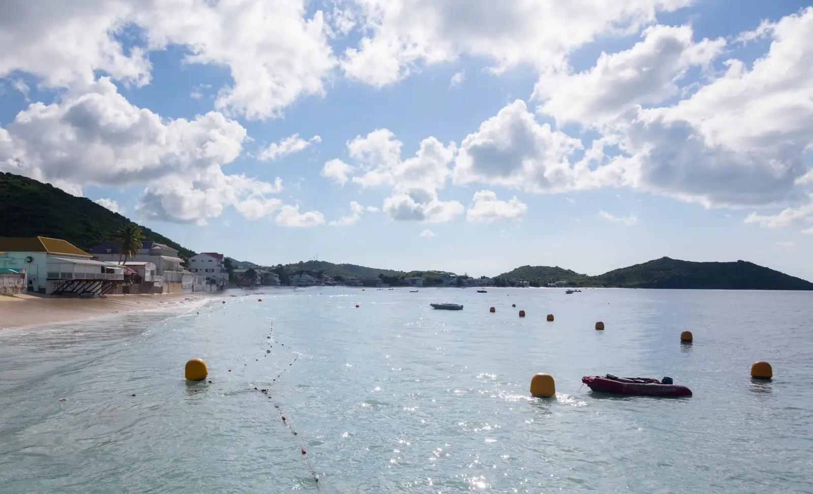 Calm water in Grand Case Bay, with buoys and houses along the beach