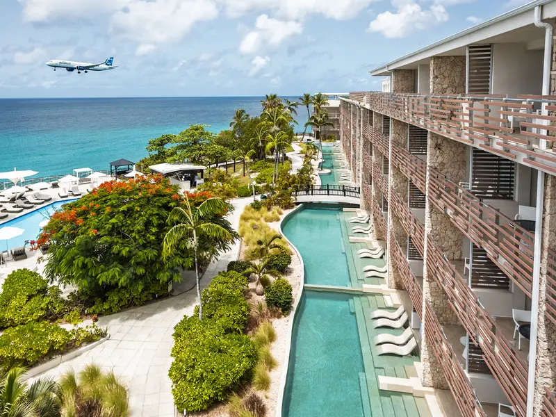 Sonesta Ocean Point, its lap pool below the suites and a plane on approach over the sea
