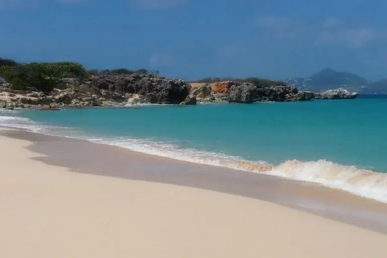 Deserted Baie Blanche beach on Tintamarre with white sand, turquoise water and rocks, view back to Saint Martin