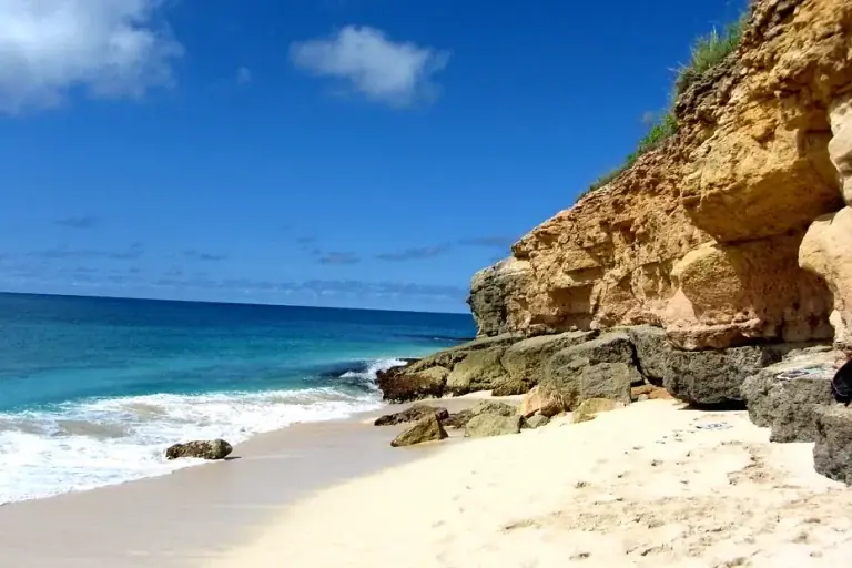 Cupecoy Beach cove with pale sand, turquoise sea and ochre sandstone cliffs