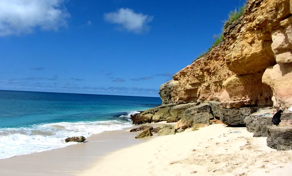 The ocher cliffs and sand of Cupecoy Beach
