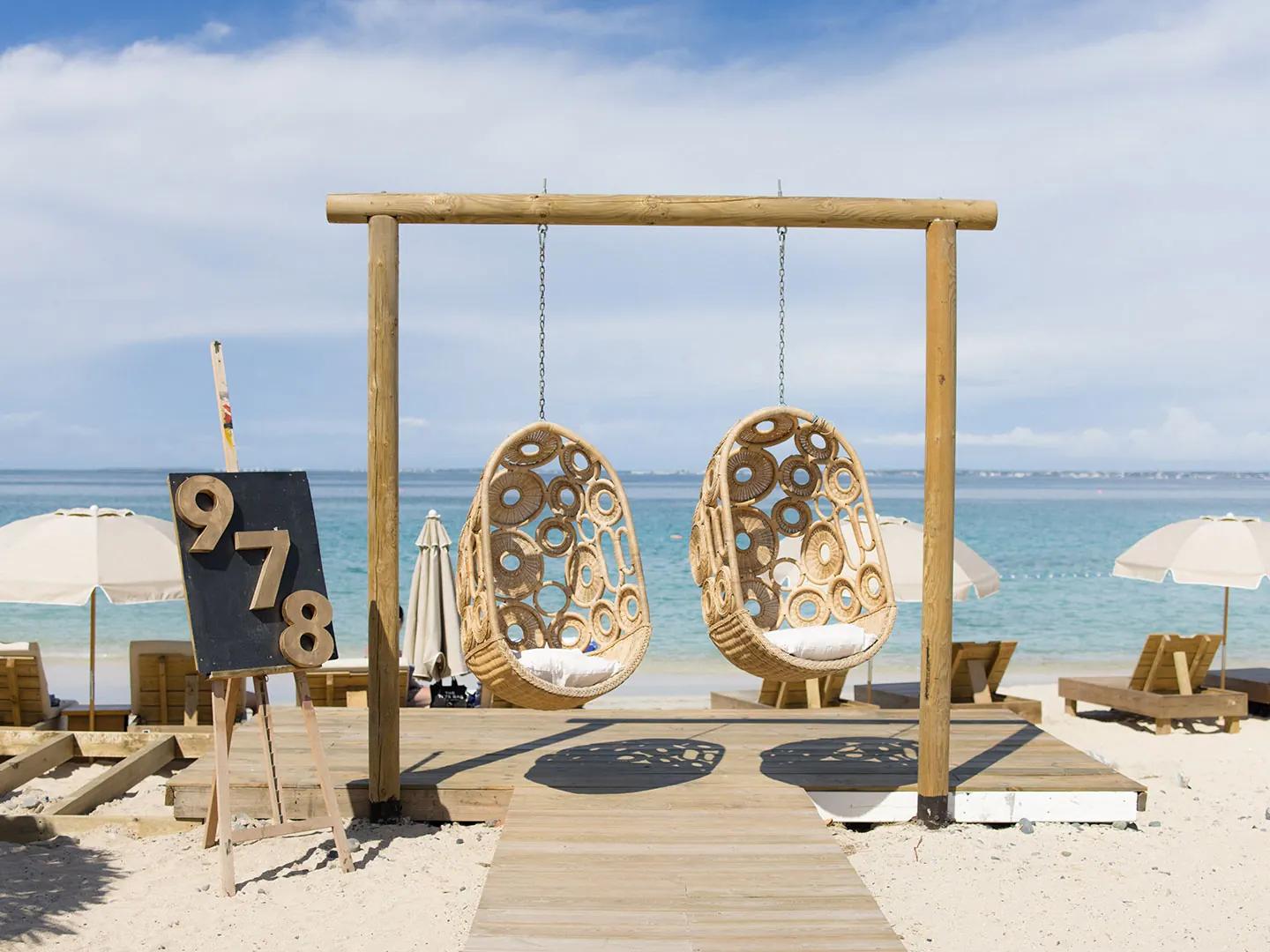 978 Beach Lounge - Hanging chairs and the 978 sign facing the sea at Friar's Bay