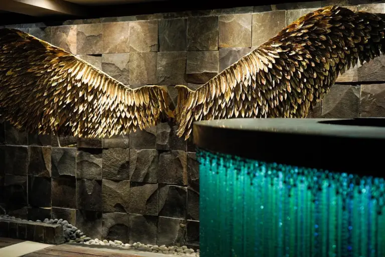 Large golden wings on a stone wall at We Culture