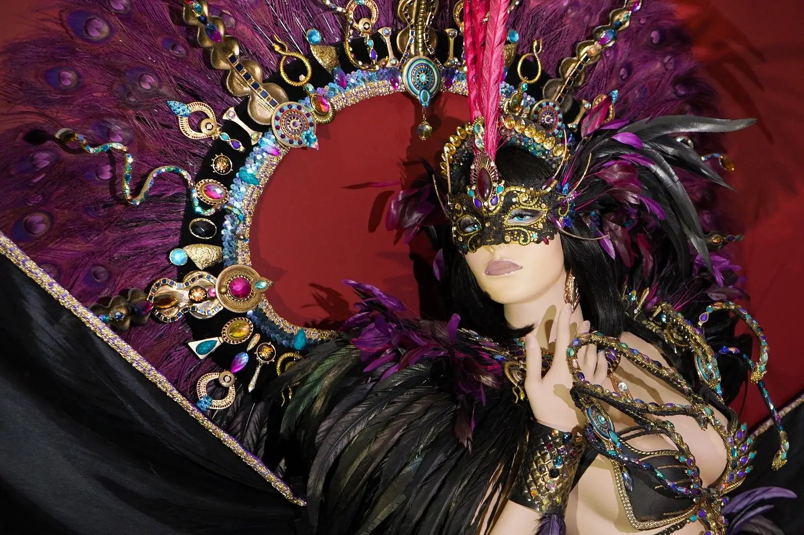 Carnival costume with purple feathers and a gold mask on display at We Culture in Maho